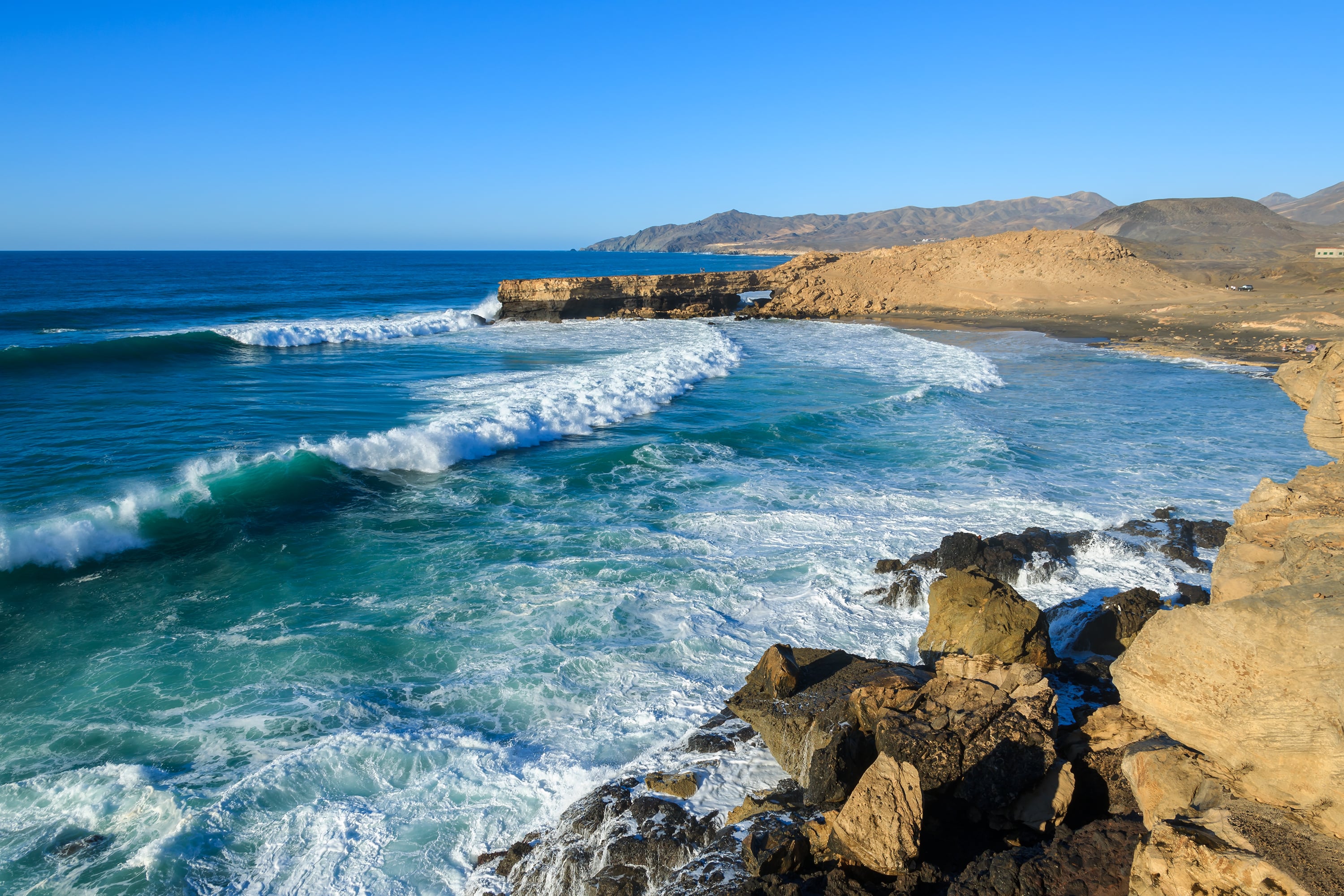 Panorama de la plage de La Pared à Fuerteventura avec une forte houle et des falaises rocheuses en arrière-plan, idéale pour les surfeurs expérimentés.